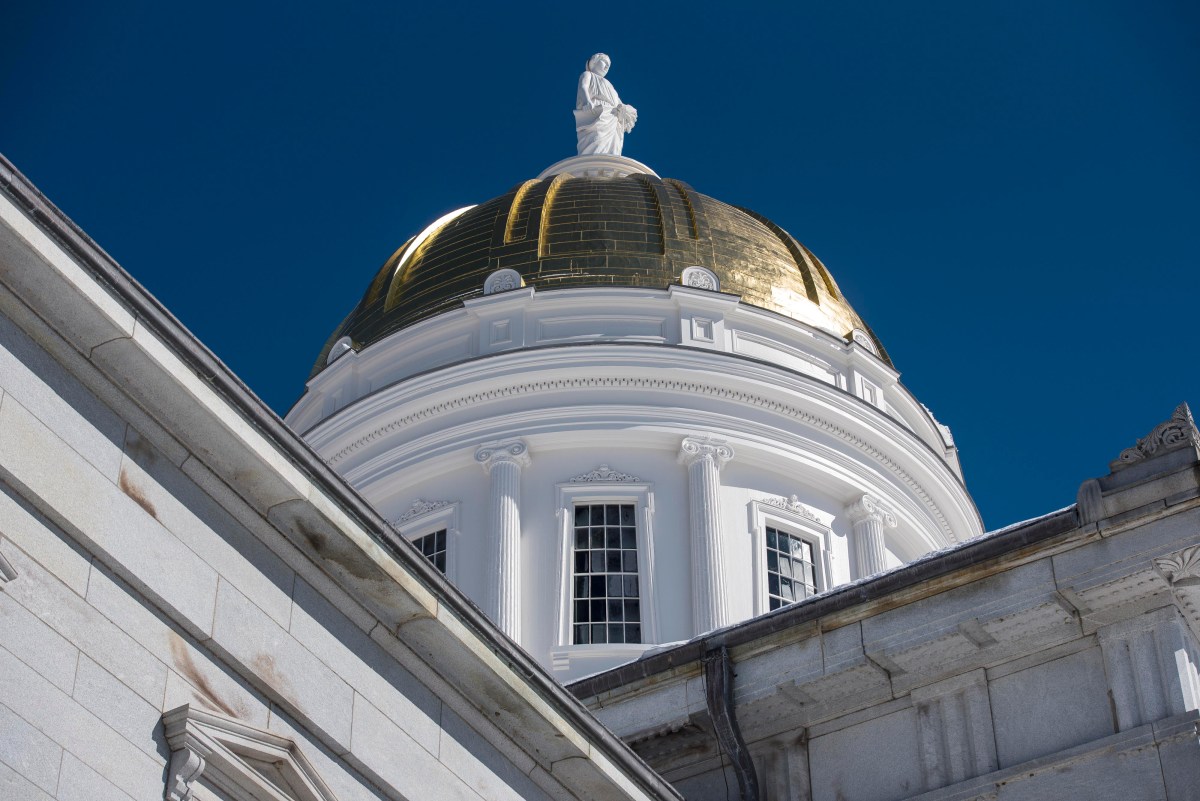 a white building with a gold dome and a statue on top.