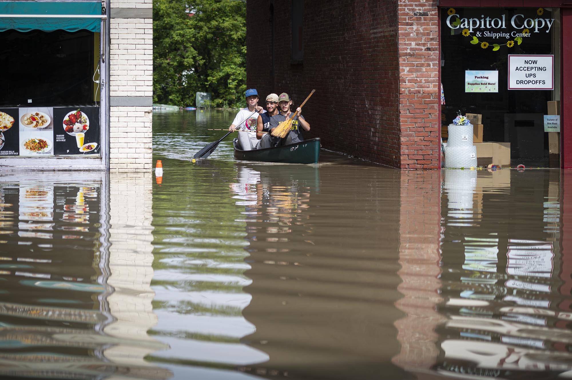 two people in a canoe on a flooded street.