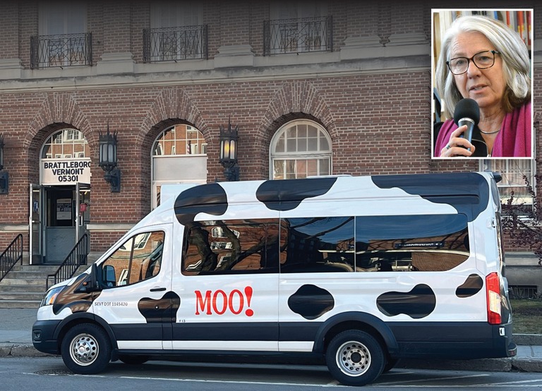 A white van with black cow spots and “MOO!” painted on the side is parked in front of a brick building. An inset shows a woman speaking into a microphone.