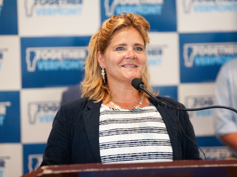 A woman stands at a podium with a microphone.